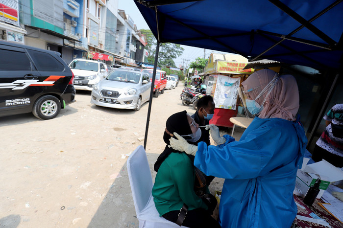 Petugas kesehatan mengambil sampel lendir pengendara saat tes swab antigen di Penyekatan Bojongsari, Depok, Jawa Barat, Minggu (16/5/2021).