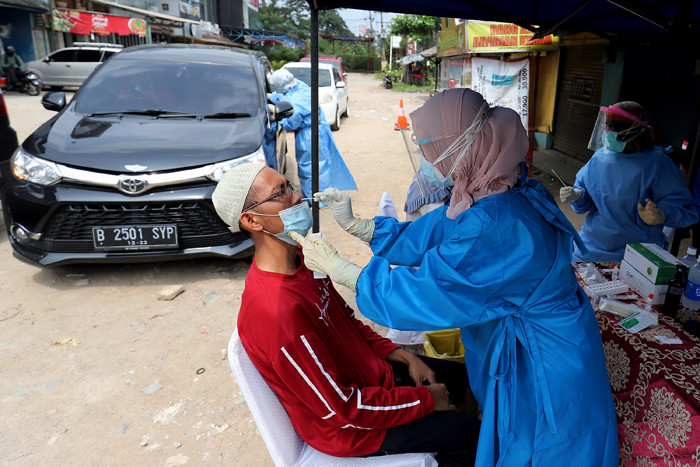 Petugas kesehatan mengambil sampel lendir pengendara saat tes swab antigen di Penyekatan Bojongsari, Depok, Jawa Barat, Minggu (16/5/2021).