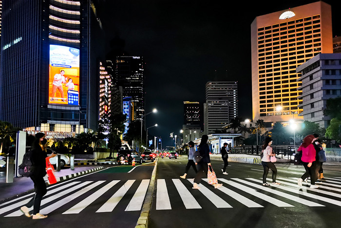 Warga pulang kerja melintasi pedestrian light controlled crossing (Pelican Crossing) di kawasan Sudirman, Jakarta Pusat, Senin (17/5/2021).