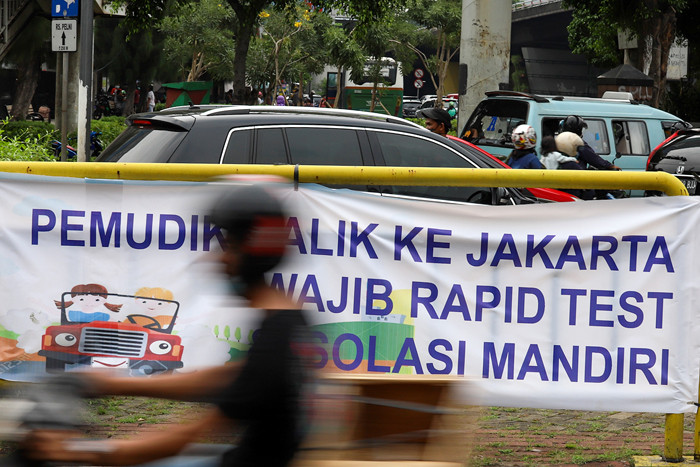 Pengendara melintasi spanduk bertuliskan himbauan kepada warga pemudik wajib test Covid-19 di Jakarta Barat, Senin (17/5/2021).