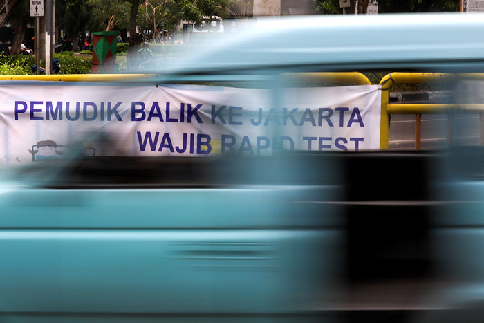 Pengendara melintasi spanduk bertuliskan himbauan kepada warga pemudik wajib test Covid-19 di Jakarta Barat, Senin (17/5/2021).