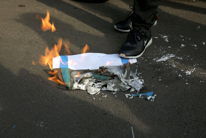 Pengunjuk rasa membakar kertas bergambar bendera Israel saat mengikuti aksi di depan Gedung Kedubes Amerika Serikat, Jakarta, Selasa (18/5/2021).