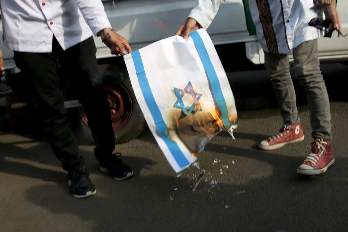 Pengunjuk rasa membakar kertas bergambar bendera Israel saat mengikuti aksi di depan Gedung Kedubes Amerika Serikat, Jakarta, Selasa (18/5/2021).