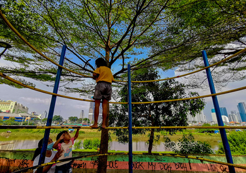 Anak-anak bermain di taman pemukiman yang berlatar belakang gedung bertingkat di Jakarta Pusat, Selasa (18/5/2021).