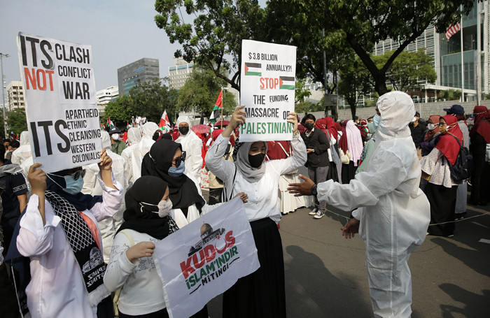 Petugas kepolisian mengenakan baju hazmat membantu pengunjuk rasa melaksanakan protokol kesehatan di depan Gedung Kedubes AS, Jakarta, Selasa (18/5/2021).
