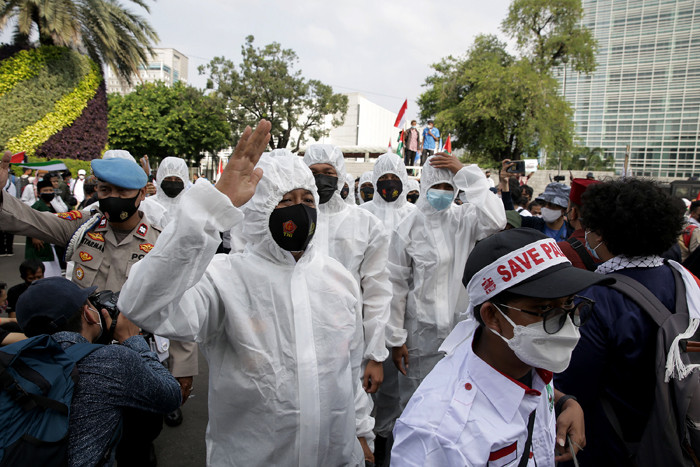Petugas kepolisian mengenakan baju hazmat membantu pengunjuk rasa melaksanakan protokol kesehatan di depan Gedung Kedubes AS, Jakarta, Selasa (18/5/2021).