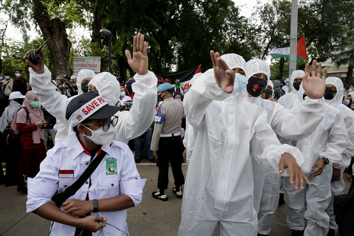 Petugas kepolisian mengenakan baju hazmat membantu pengunjuk rasa melaksanakan protokol kesehatan di depan Gedung Kedubes AS, Jakarta, Selasa (18/5/2021).