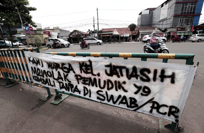 Pengendara melintasi spanduk bertuliskan himbauan kepada warga pemudik wajib test Covid-19 di kawasan Jatiasih, Kota Bekasi, Jawa Barat, Selasa (18/5/2021).