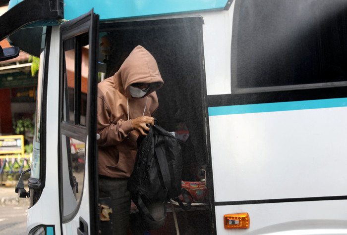 Petugas damkar menyemprotkan cairan disinfektan kepada bus yang tiba dari daerah di terminal Kampung Rambutan, Jakarta Timur, Rabu (19/5/2021).