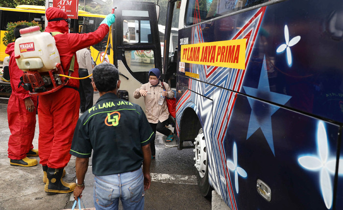 Petugas damkar menyemprotkan cairan disinfektan kepada bus yang tiba dari daerah di terminal Kampung Rambutan, Jakarta Timur, Rabu (19/5/2021).