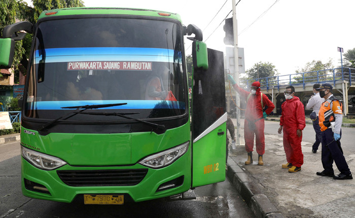 Petugas damkar menyemprotkan cairan disinfektan kepada bus yang tiba dari daerah di terminal Kampung Rambutan, Jakarta Timur, Rabu (19/5/2021).