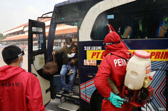 Petugas damkar menyemprotkan cairan disinfektan kepada bus yang tiba dari daerah di terminal Kampung Rambutan, Jakarta Timur, Rabu (19/5/2021).