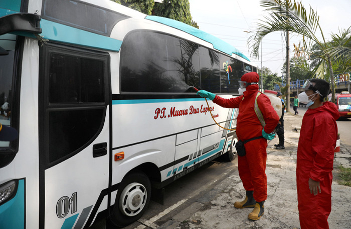 Petugas damkar menyemprotkan cairan disinfektan kepada bus yang tiba dari daerah di terminal Kampung Rambutan, Jakarta Timur, Rabu (19/5/2021).