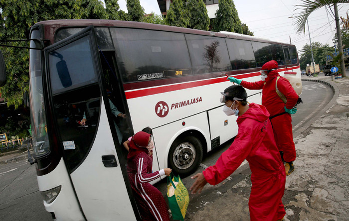 Petugas pemadam menyemprotkan cairan disinfektan kepada pemudik yang baru tiba di Terminal Kampung Rambutan, Jakarta, Rabu (19/5/2021).
