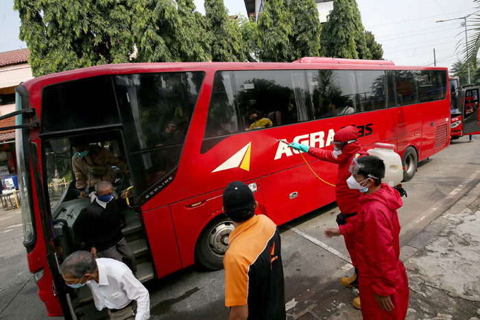 Petugas pemadam menyemprotkan cairan disinfektan kepada pemudik yang baru tiba di Terminal Kampung Rambutan, Jakarta, Rabu (19/5/2021).