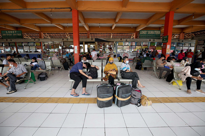 Petugas pemadam menyemprotkan cairan disinfektan kepada pemudik yang baru tiba di Terminal Kampung Rambutan, Jakarta, Rabu (19/5/2021).