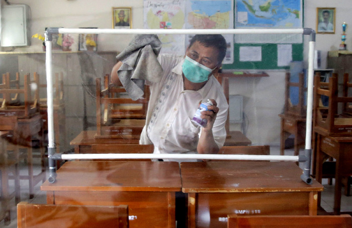 Petugas menyiapkan ruangan kelas yang akan digunakan untuk seleksi Penerimaan Peserta Didik Baru (PPDB) di SMPN 115 Jakarta, Jumat (21/5/2021).