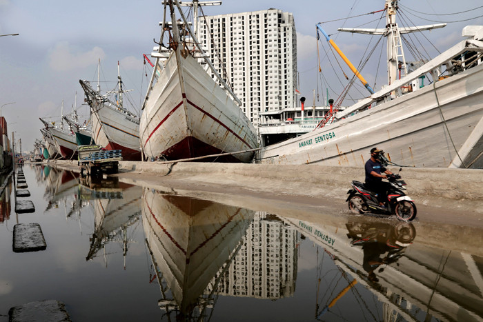 Pengendara melintasi kapal yang bersandar di Pelabuhan Sunda Kelapa, Jakart Utara, Jumat (21/5/2021).