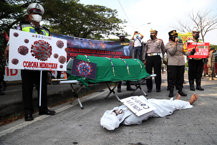 Sosok pocong korban Covid-19 jadi-jadian mengejutkan pengguna jalan saat melintas di pos penyekatan Polres Pelabuhan Tanjung Perak Surabaya, Sabtu (22/5/2021).