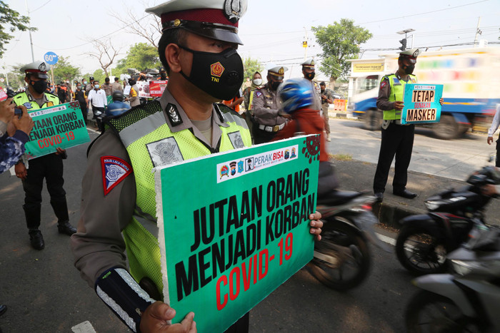 Sosok pocong korban Covid-19 jadi-jadian mengejutkan pengguna jalan saat melintas di pos penyekatan Polres Pelabuhan Tanjung Perak Surabaya, Sabtu (22/5/2021).