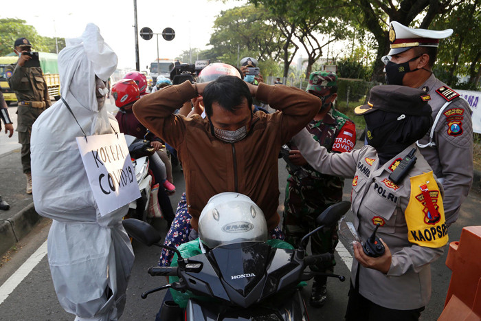 Sosok pocong korban Covid-19 jadi-jadian mengejutkan pengguna jalan saat melintas di pos penyekatan Polres Pelabuhan Tanjung Perak Surabaya, Sabtu (22/5/2021).