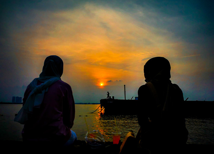 Suasana aktivitas warga sore menjelang malam di kawasan pelabuhan kaliadem, Jakarta Utara, Minggu (23/5/2021).