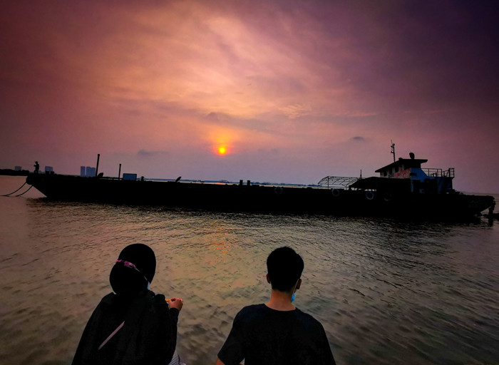 Suasana aktivitas warga sore menjelang malam di kawasan pelabuhan kaliadem, Jakarta Utara, Minggu (23/5/2021).