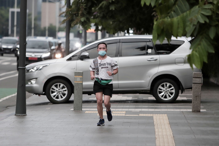 Pekerja kantor mengenakan masker berjalan di pedestrian Jalan MH Thamrin, Jakarta Pusat, Senin (24/5/2021).