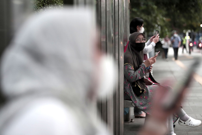 Pekerja kantor mengenakan masker berjalan di pedestrian Jalan MH Thamrin, Jakarta Pusat, Senin (24/5/2021).