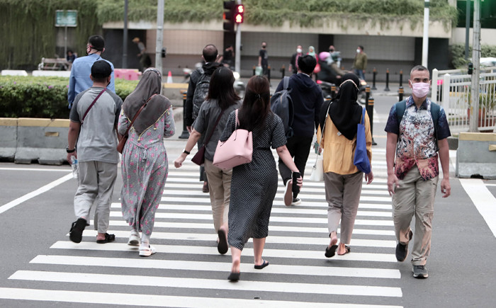 Pekerja kantor mengenakan masker berjalan di pedestrian Jalan MH Thamrin, Jakarta Pusat, Senin (24/5/2021).
