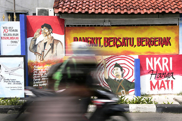 Pengendara melintasi mural bertema nilai-nilai Pancasila dan nilai-nilai kepahlawanan di kawasan Galur, Jakarta Pusat, Senin (24/5/2021).
