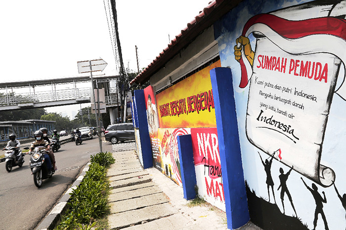 Pengendara melintasi mural bertema nilai-nilai Pancasila dan nilai-nilai kepahlawanan di kawasan Galur, Jakarta Pusat, Senin (24/5/2021).