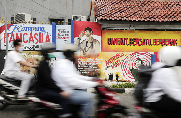 Pengendara melintasi mural bertema nilai-nilai Pancasila dan nilai-nilai kepahlawanan di kawasan Galur, Jakarta Pusat, Senin (24/5/2021).
