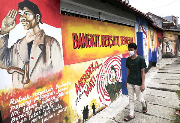 Pengendara melintasi mural bertema nilai-nilai Pancasila dan nilai-nilai kepahlawanan di kawasan Galur, Jakarta Pusat, Senin (24/5/2021).