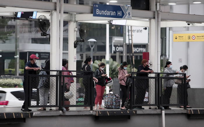 Calon penumpang menunggu bus Transjakarta di halte Bundaran HI, Jakarta, Senin (24/5/2021).