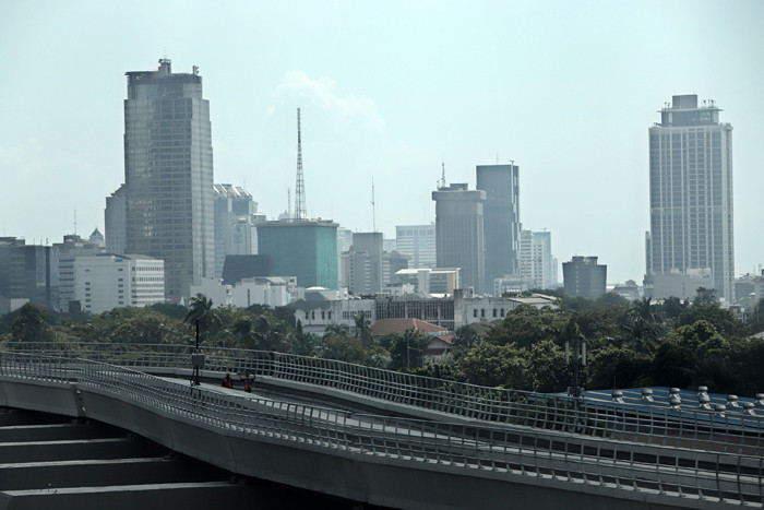 Pekerja berjalan di jalur Light Rail Transit di kawasan Jalan Rasuna Said, Jakarta, Kamis (27/5/2021).