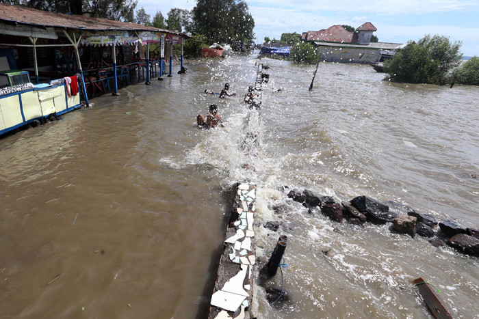 Sejumlah anak bermain dibibir pantai ketika banjir rob menerjang kawasan wisata Kenjeran Park Surabaya, Jawa Timur, Jumat (28/5/2021).