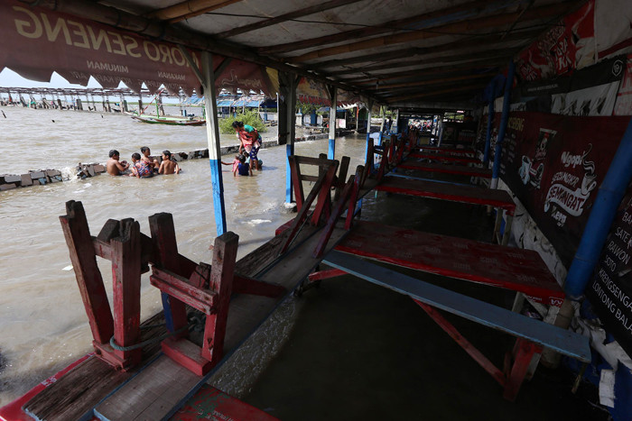 Sejumlah anak bermain dibibir pantai ketika banjir rob menerjang kawasan wisata Kenjeran Park Surabaya, Jawa Timur, Jumat (28/5/2021).