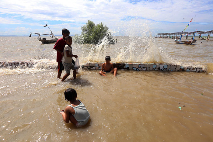 Sejumlah anak bermain dibibir pantai ketika banjir rob menerjang kawasan wisata Kenjeran Park Surabaya, Jawa Timur, Jumat (28/5/2021).