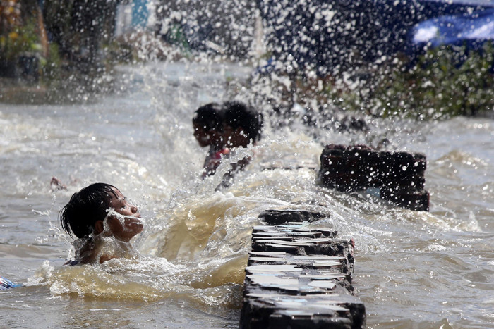 Sejumlah anak bermain dibibir pantai ketika banjir rob menerjang kawasan wisata Kenjeran Park Surabaya, Jawa Timur, Jumat (28/5/2021).