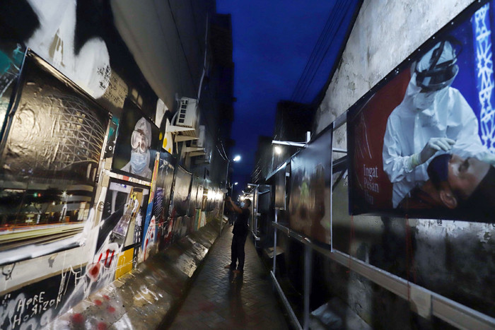 Warga melihat pameran foto Meredah Covid-19 di kawasan Gang Pasar Lama, Jalan Kisamaun, Tangerang, Banten, Sabtu (29/5/2021).