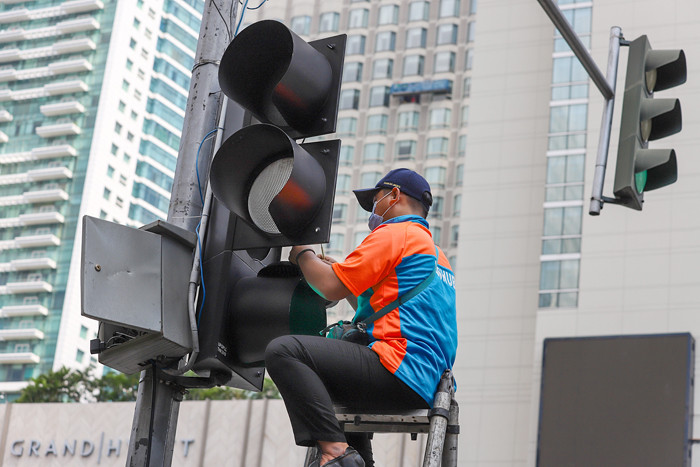 Petugas memperbaiki lampu lalu lintas di penyebrangan orang di Bundaran HI, Jakarta Pusat, Minggu (30/5/2021).