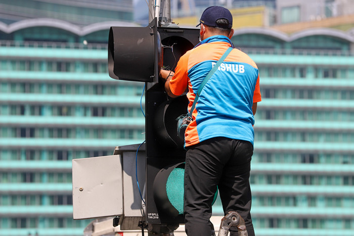 Petugas memperbaiki lampu lalu lintas di penyebrangan orang di Bundaran HI, Jakarta Pusat, Minggu (30/5/2021).