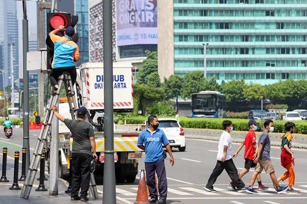 Petugas memperbaiki lampu lalu lintas di penyebrangan orang di Bundaran HI, Jakarta Pusat, Minggu (30/5/2021).
