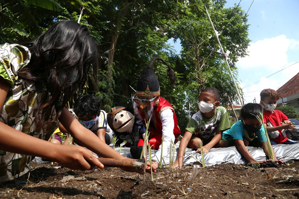 Punakawan yang diperankan oleh pendongeng Kak Harris mengajak anak-anak menanam sayuran di sepadan sungai Kalibokor Surabaya, Jawa Timur, Kamis (3/6/2021).
