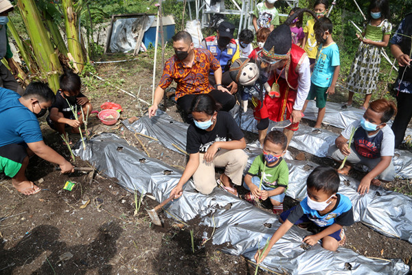 Punakawan yang diperankan oleh pendongeng Kak Harris mengajak anak-anak menanam sayuran di sepadan sungai Kalibokor Surabaya, Jawa Timur, Kamis (3/6/2021).