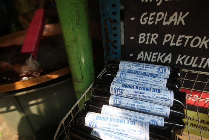 Penjual mengaduk dodol saat dimasak sebelum akhirnya dapat dijual di kawasan Perkampungan Budaya Betawi Setu Babakan, Jagakarsa, Minggu (6/6/2021).