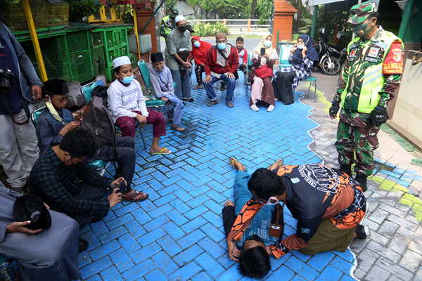 Peserta bersembunyi dibawah meja ketika mengikuti simulasi bencana alam di Koramil Tipe A 0831/04 Sukolilo Surabaya, Jawa Timur, Minggu (6/6/2021).