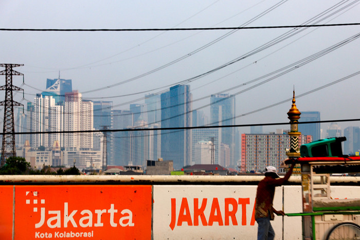 Warga saat melintas berlatar belakang gedung bertingkat di Jalan layang Tomang, Jakarta Barat, Senin (7/6/2021).