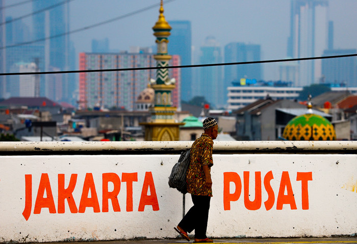 Warga saat melintas berlatar belakang gedung bertingkat di Jalan layang Tomang, Jakarta Barat, Senin (7/6/2021).